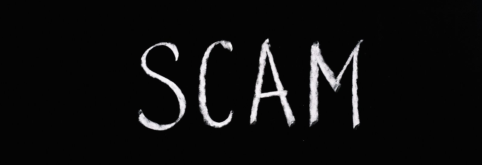 Photo with the word "SCAM" in chalk on a blackboard