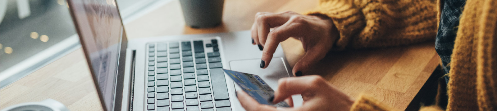 Woman typing on computer with credit card in hand.