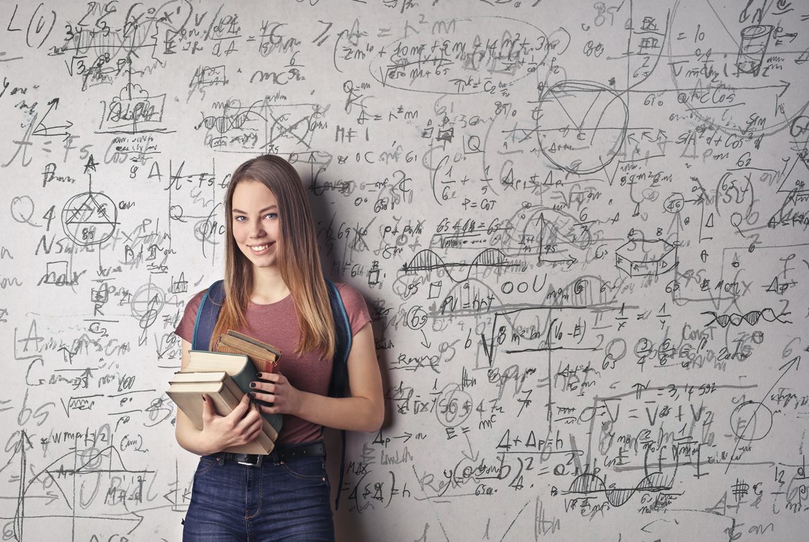 Student leaning on blackboard with formulas