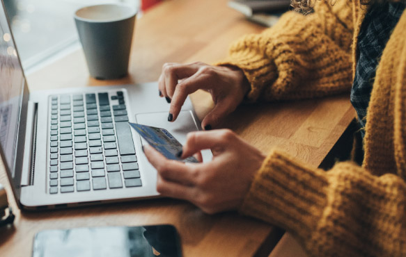 Woman on computer with card in hand.