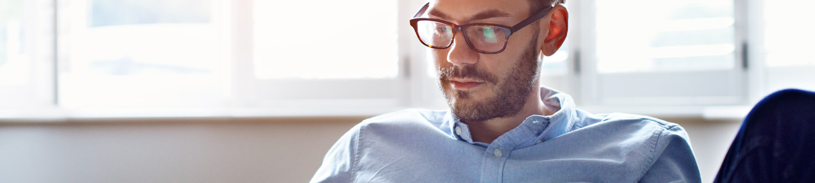 Man sits in home with device in hand.